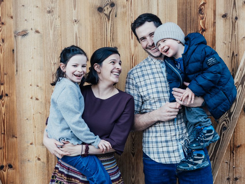 Erholungsurlaub im Chalet im Stubaital Glückliche Familie mit zwei Kindern vor einer Holzfassade