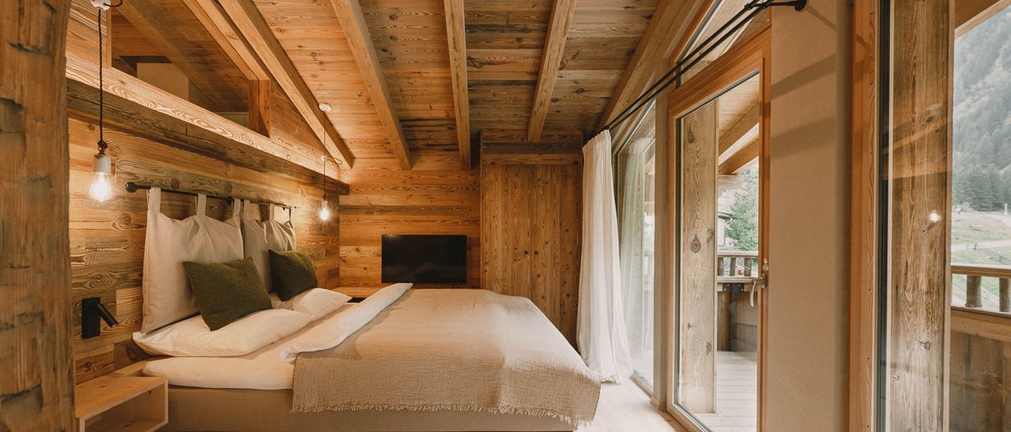 Erholungsurlaub im Chalet im Stubaital Gemütliches Schlafzimmer in einer Holzhütte mit großem Bett und Balkon