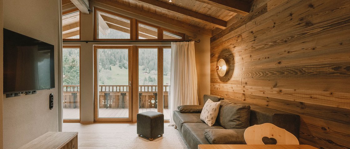 Erholungsurlaub im Chalet im Stubaital Gemütliches Wohnzimmer mit Holzwänden und großen Fenstern mit Bergblick