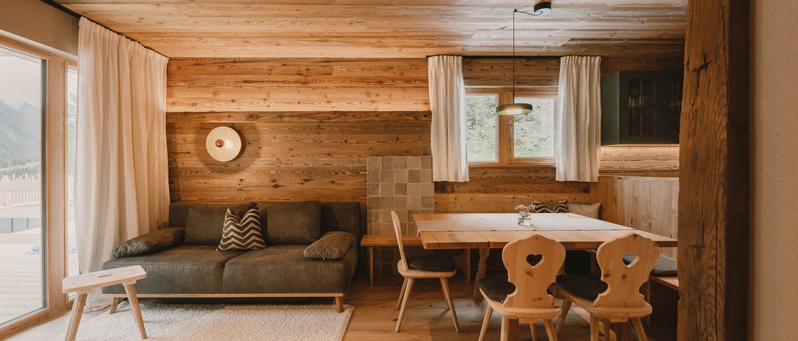 Erholungsurlaub im Chalet im Stubaital Gemütliches Wohnzimmer mit Holzvertäfelung, Sofa und Esstisch mit Stühlen