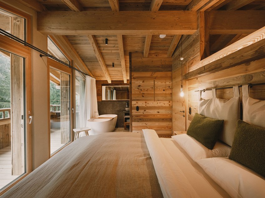 Erholungsurlaub im Chalet im Stubaital Gemütliches Schlafzimmer mit Holzwänden, Bett und freistehender Badewanne