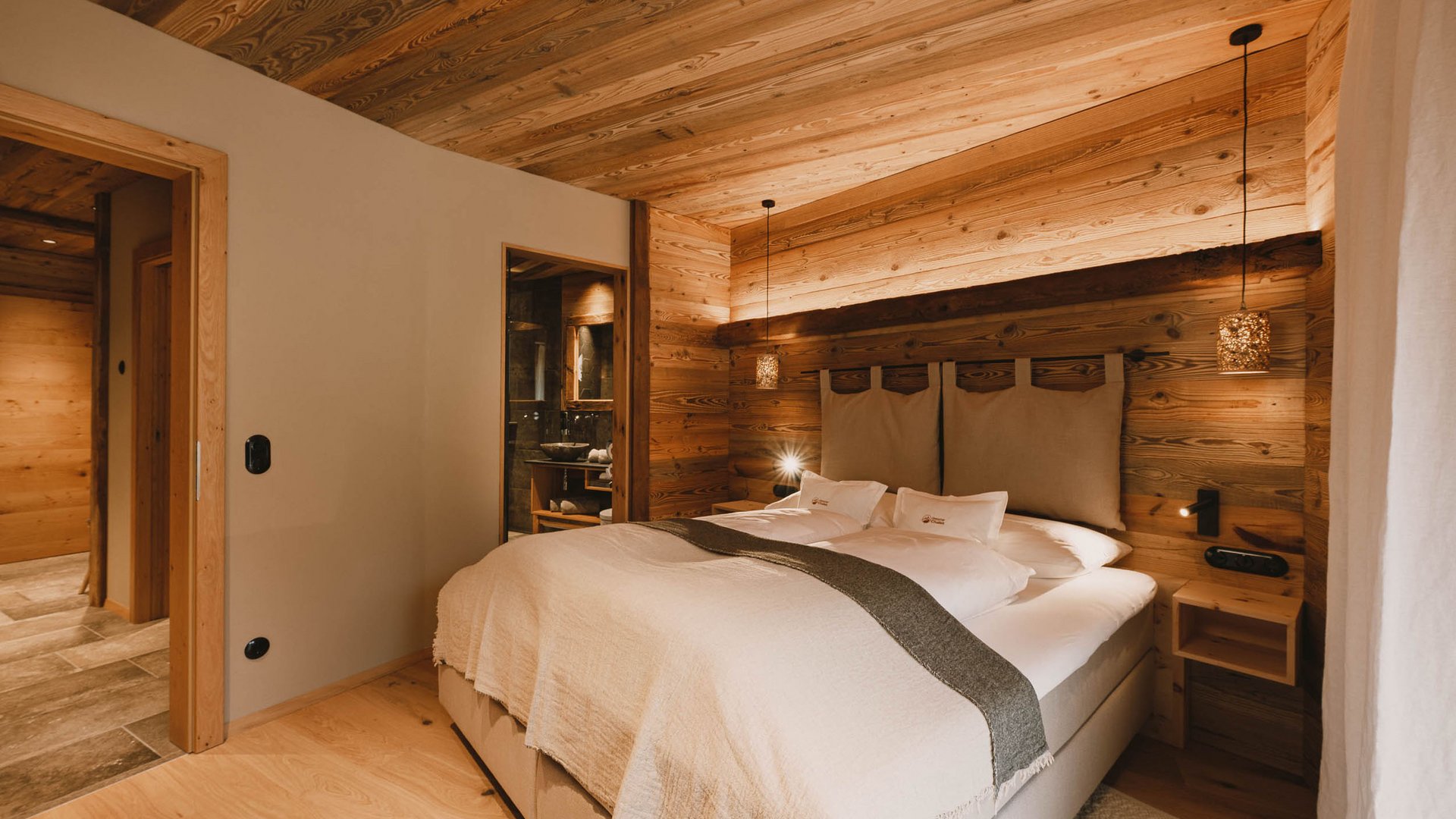 Erholungsurlaub im Chalet im Stubaital Gemütliches Schlafzimmer mit Holzwänden und großem Bett in warmem Licht